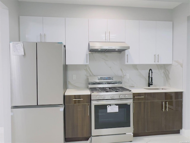 kitchen featuring decorative backsplash, refrigerator, gas range gas stove, sink, and white cabinets