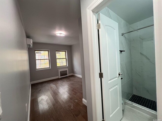 bathroom with an AC wall unit, a shower with door, and hardwood / wood-style flooring