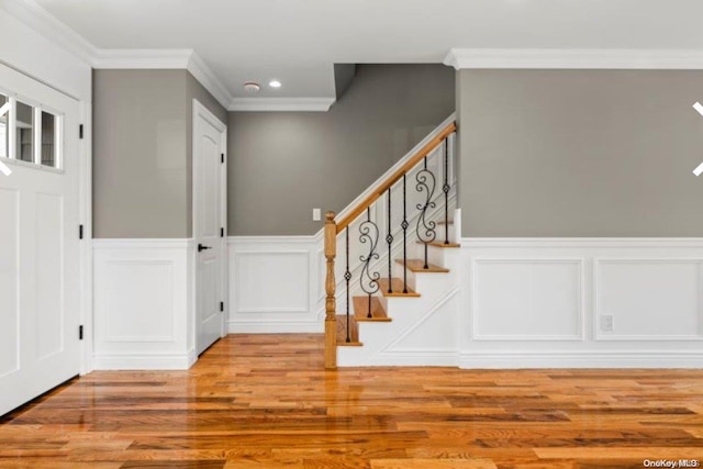 entryway with wood-type flooring and crown molding