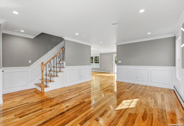 unfurnished living room with a baseboard heating unit, ornamental molding, and light hardwood / wood-style flooring