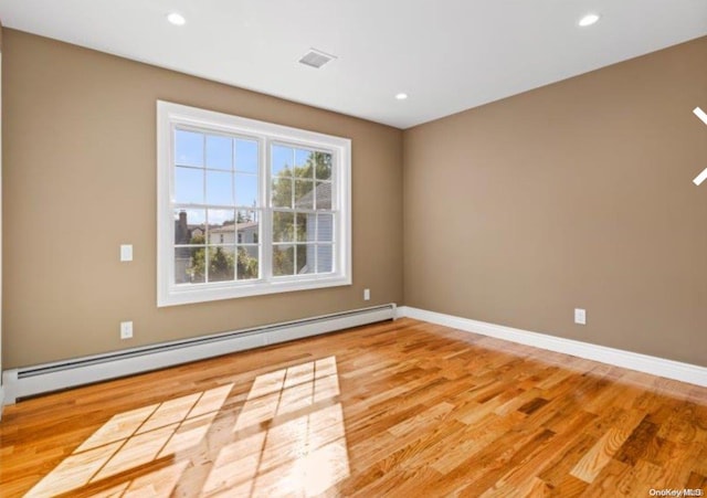 unfurnished room featuring a baseboard radiator and light hardwood / wood-style floors