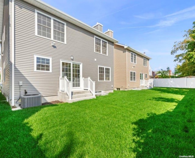 rear view of property with a lawn and cooling unit