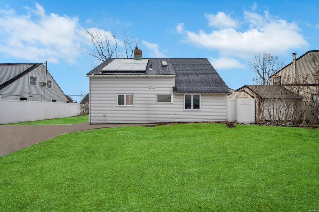 back of house featuring a lawn and solar panels