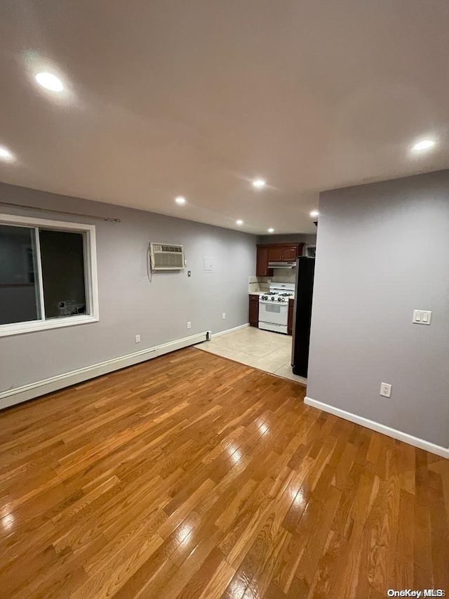 unfurnished living room featuring a wall unit AC, light hardwood / wood-style flooring, and baseboard heating