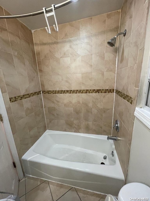 bathroom featuring toilet, tile patterned floors, and tiled shower / bath