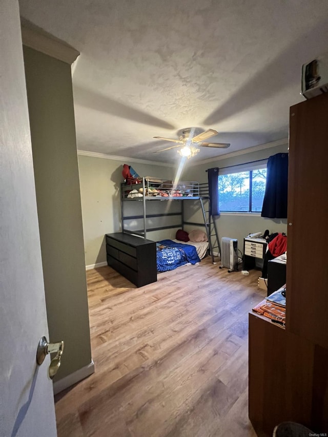 bedroom featuring radiator, light hardwood / wood-style floors, ceiling fan, and crown molding