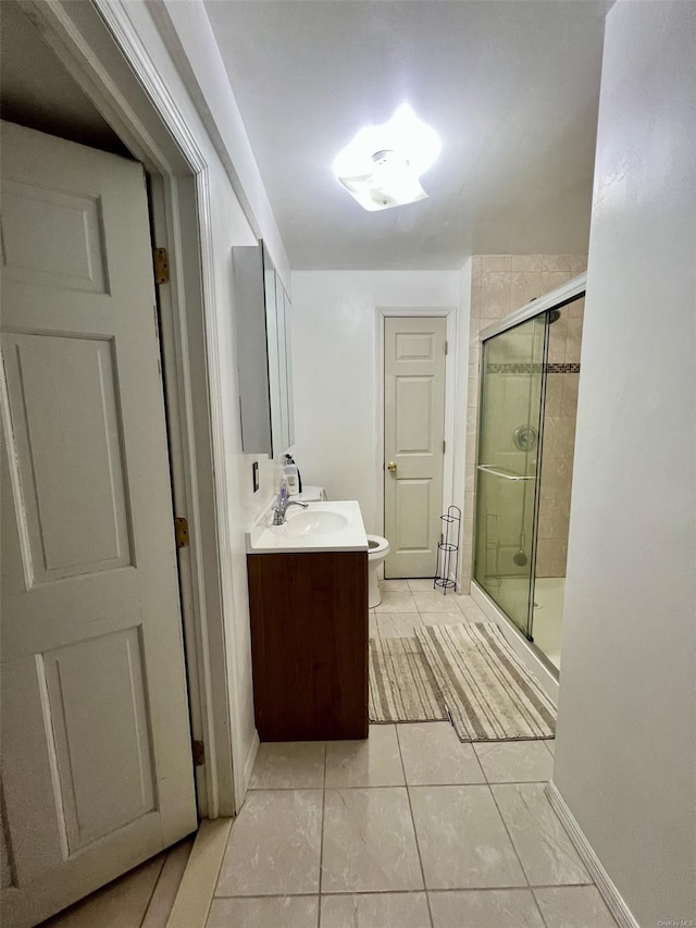 bathroom featuring tile patterned flooring, vanity, toilet, and a shower with door