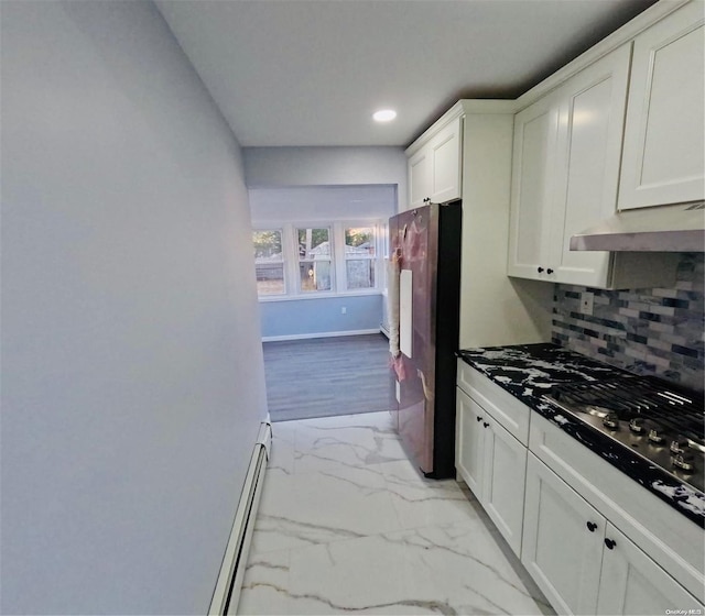 kitchen featuring backsplash, white cabinets, a baseboard radiator, stainless steel refrigerator, and gas cooktop