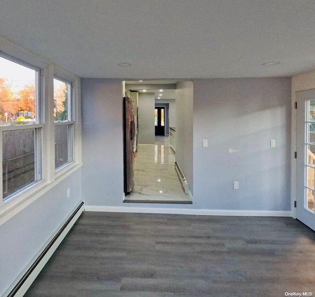 unfurnished room featuring baseboard heating and dark wood-type flooring