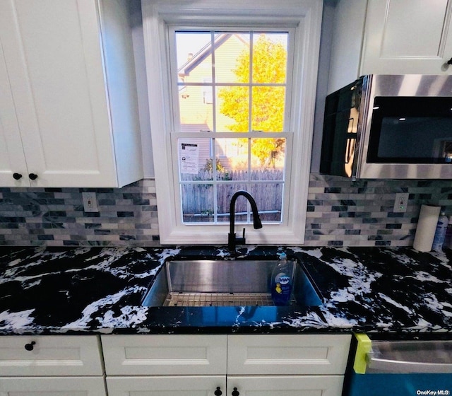 kitchen with tasteful backsplash, white cabinetry, and sink