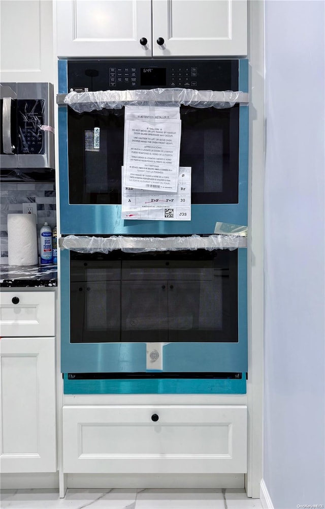 interior details with white cabinetry, backsplash, and appliances with stainless steel finishes