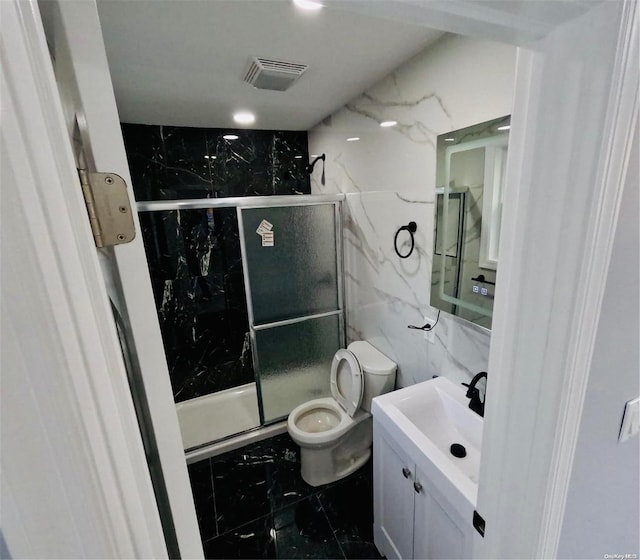 bathroom featuring vanity, toilet, and a shower with door