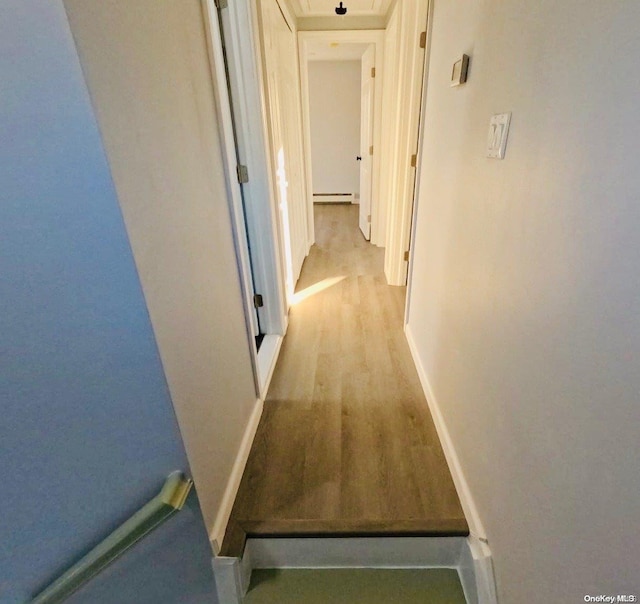 hall with light hardwood / wood-style floors and a baseboard heating unit