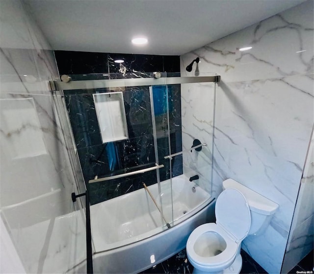 bathroom featuring toilet and bath / shower combo with glass door