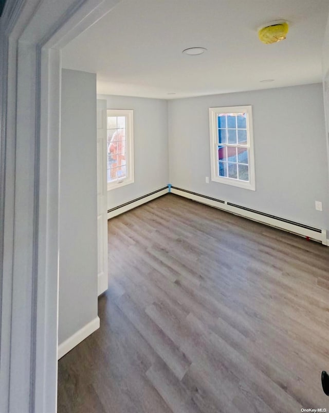 spare room with hardwood / wood-style flooring, a healthy amount of sunlight, and a baseboard heating unit