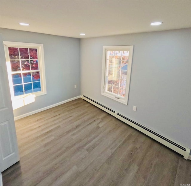 unfurnished room with baseboard heating and light hardwood / wood-style floors