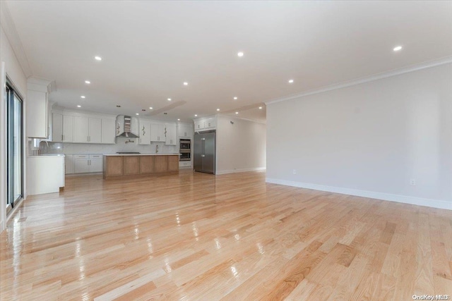 unfurnished living room featuring light hardwood / wood-style flooring, crown molding, and sink