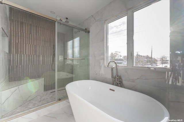 bathroom featuring a healthy amount of sunlight, tile walls, and separate shower and tub