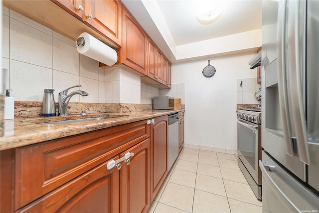 kitchen with decorative backsplash, appliances with stainless steel finishes, light stone countertops, sink, and range hood