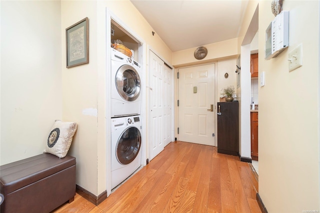 laundry area featuring light wood-type flooring and stacked washer and dryer