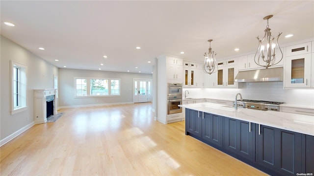 kitchen featuring pendant lighting, white cabinets, decorative backsplash, appliances with stainless steel finishes, and light hardwood / wood-style floors