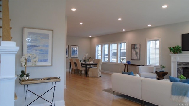 living room with a high end fireplace, light hardwood / wood-style flooring, and a wealth of natural light