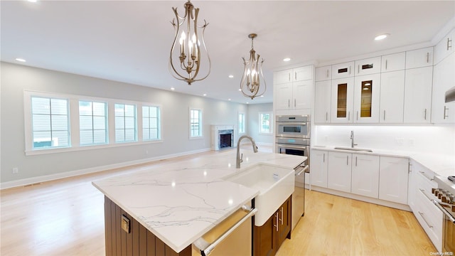 kitchen with appliances with stainless steel finishes, sink, decorative light fixtures, white cabinets, and a kitchen island