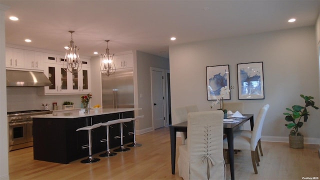 kitchen with a kitchen island, range hood, stainless steel range, light hardwood / wood-style floors, and white cabinetry