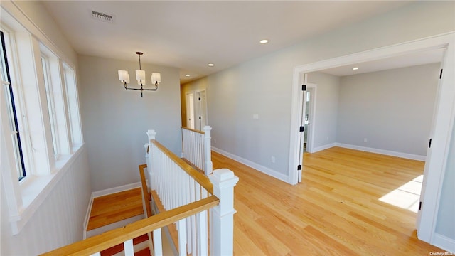 hall with a chandelier, light hardwood / wood-style floors, and a wealth of natural light