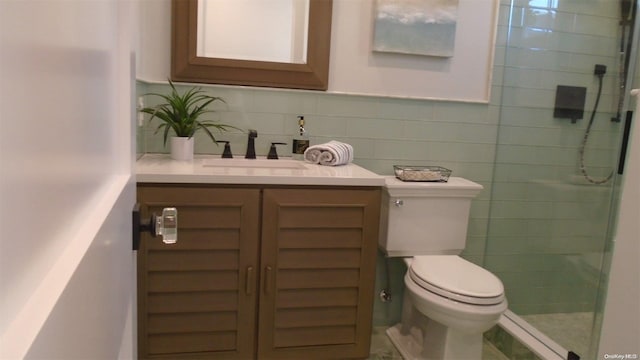 bathroom featuring vanity, a shower with door, toilet, tile walls, and tasteful backsplash