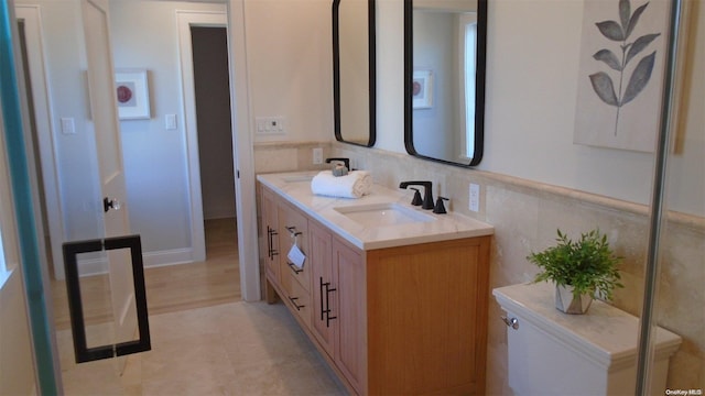 bathroom featuring vanity, tile walls, and toilet