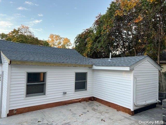 59 Port Washington Ave, Sound Beach, NY 11789 - view of property exterior featuring a shingled roof, a patio, and crawl space