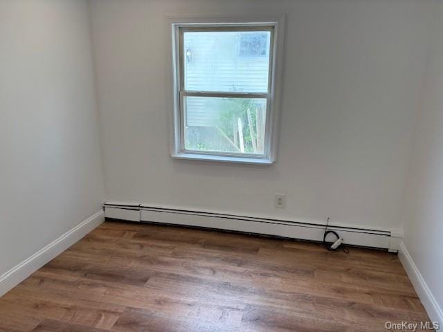 59 Port Washington Ave, Sound Beach, NY 11789 - unfurnished room featuring a baseboard heating unit, wood finished floors, and baseboards