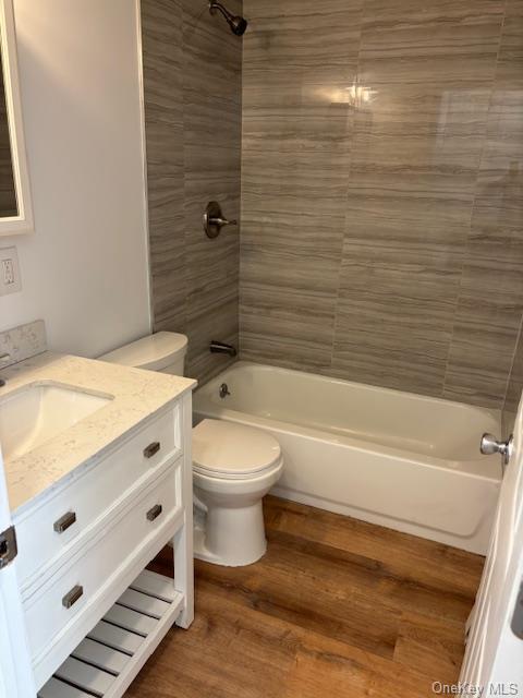 59 Port Washington Ave, Sound Beach, NY 11789 - full bathroom featuring vanity, shower / bath combination, toilet, and wood finished floors