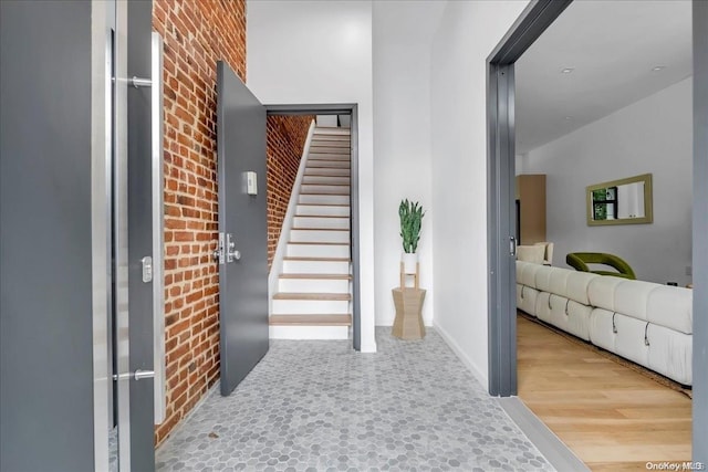 stairs featuring hardwood / wood-style flooring and brick wall