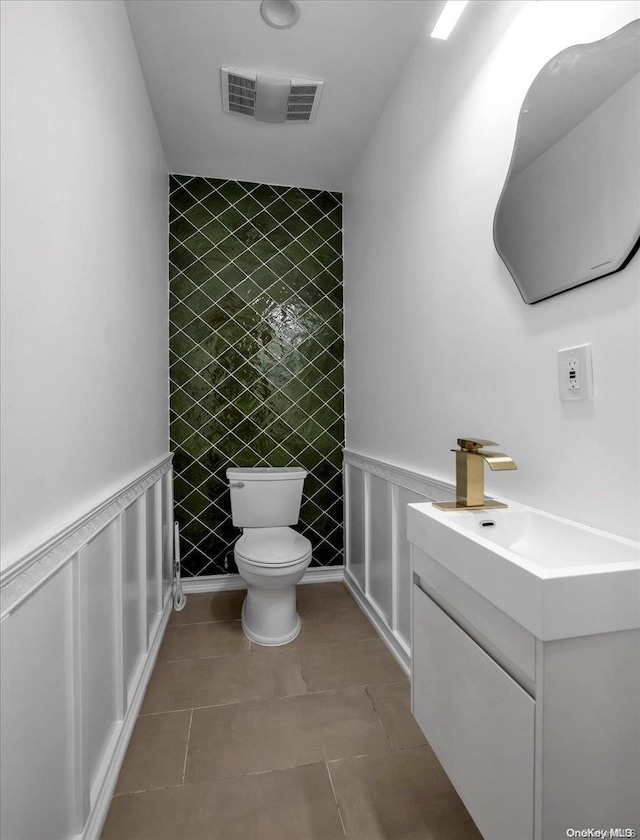 bathroom featuring tile patterned flooring, vanity, toilet, and tile walls