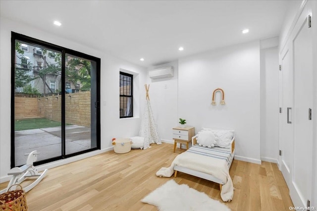 living area with a wall mounted air conditioner and wood-type flooring