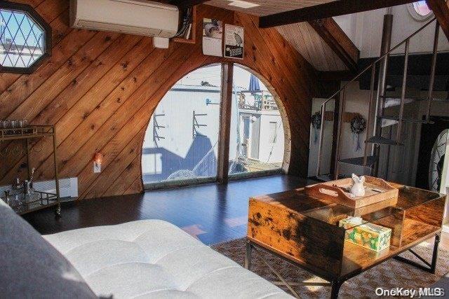 living room featuring wood walls, a healthy amount of sunlight, and a wall mounted air conditioner