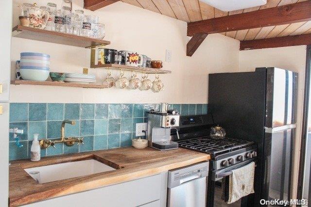 kitchen with sink, wooden ceiling, beamed ceiling, decorative backsplash, and appliances with stainless steel finishes