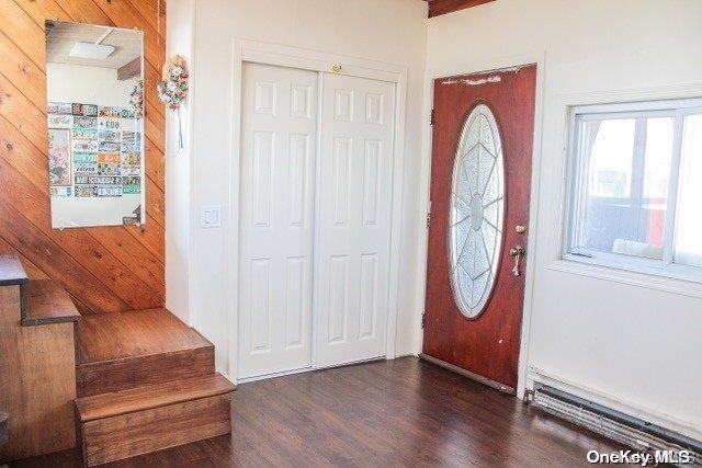 foyer featuring wood walls, dark wood-type flooring, and a baseboard radiator