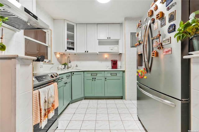 kitchen featuring white cabinets, wall chimney range hood, green cabinetry, light tile patterned floors, and stainless steel appliances