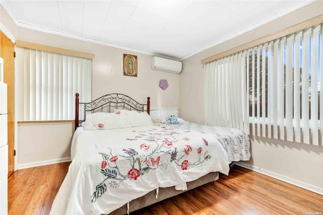 bedroom featuring hardwood / wood-style flooring, a wall unit AC, and ornamental molding