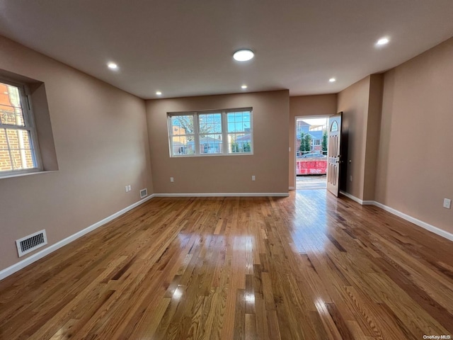 empty room with plenty of natural light and hardwood / wood-style floors