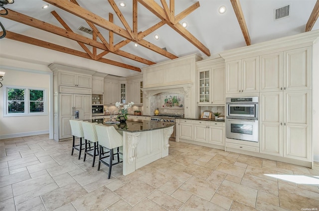 kitchen with beam ceiling, high quality appliances, dark stone counters, and tasteful backsplash