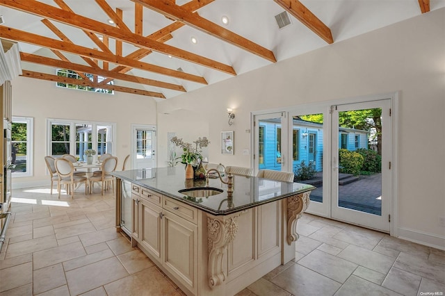 kitchen with dark stone countertops, a center island with sink, plenty of natural light, and sink