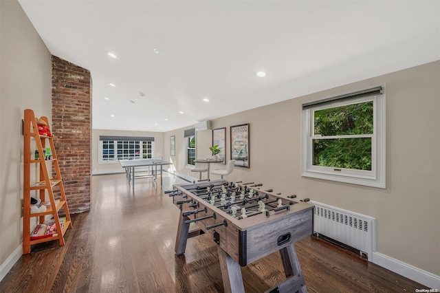 game room featuring dark hardwood / wood-style floors, radiator, and lofted ceiling