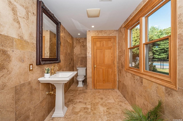 bathroom featuring tile walls and toilet