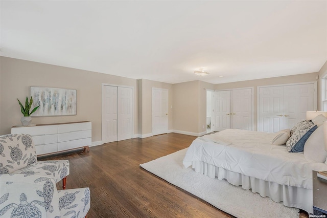 bedroom with dark hardwood / wood-style floors and multiple closets