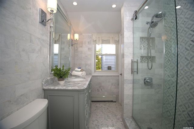 bathroom featuring baseboard heating, toilet, vanity, a shower with shower door, and tile walls