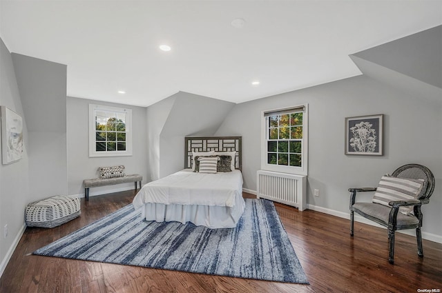 bedroom featuring multiple windows, dark hardwood / wood-style flooring, radiator, and lofted ceiling